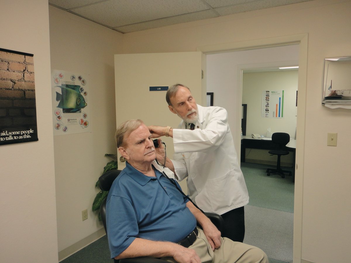 Médico realizando exame auditivo em paciente idoso