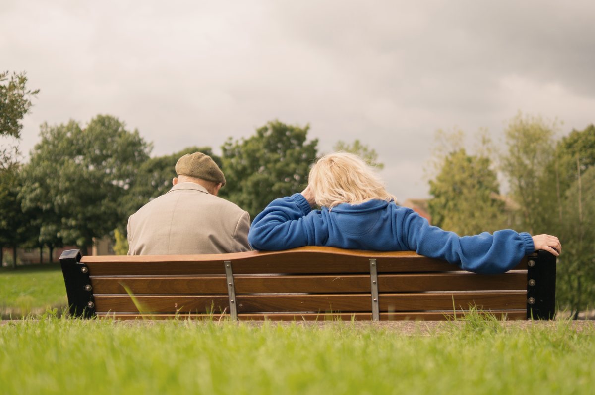 Casal de idosos sentado em banco de praça, representando o tempo de contribuição ao longo da vida